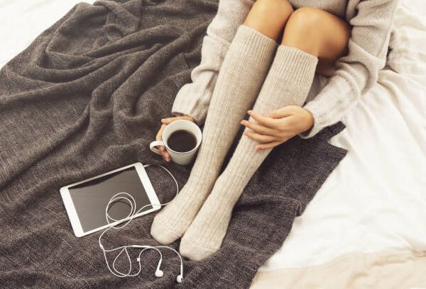 Woman in warm woolen stockings is drinking hot coffee at cold winter day